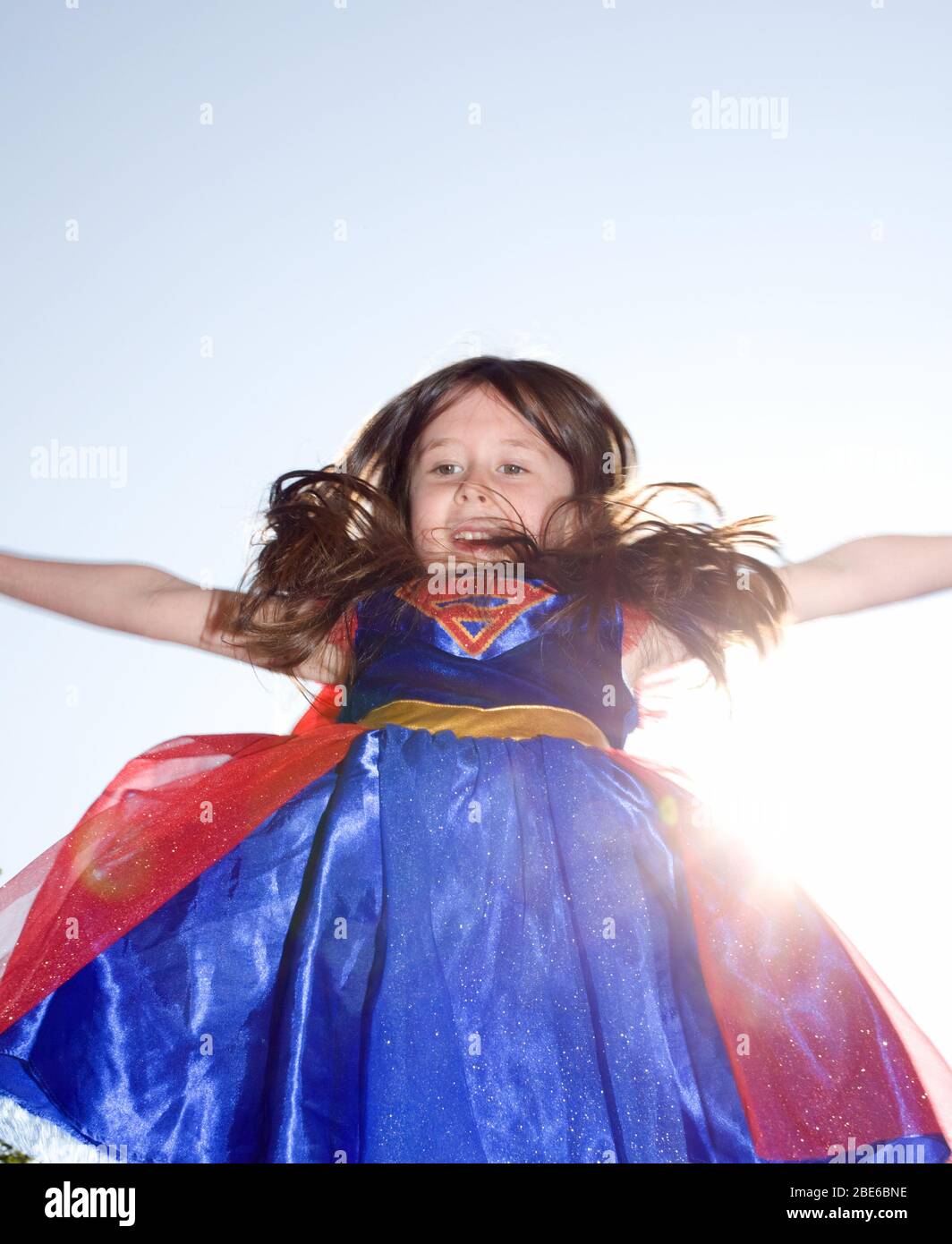 Jeune fille vêtue de super fille sautant dans l'air Banque D'Images