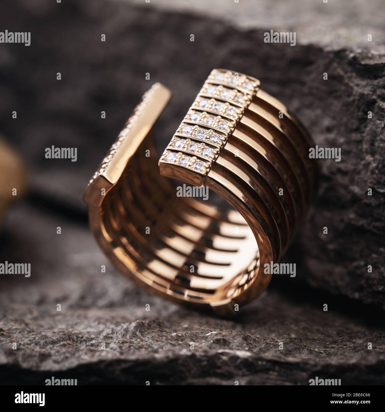 Bague dorée féminine décorée de petits joyaux sur une surface en pierre, gros plan. Banque D'Images