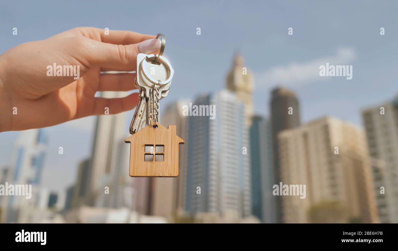 Concept d'achat immobilier. La fille tient les clés d'une nouvelle maison sur le fond d'un gratte-ciel de Dubaï. Banque D'Images