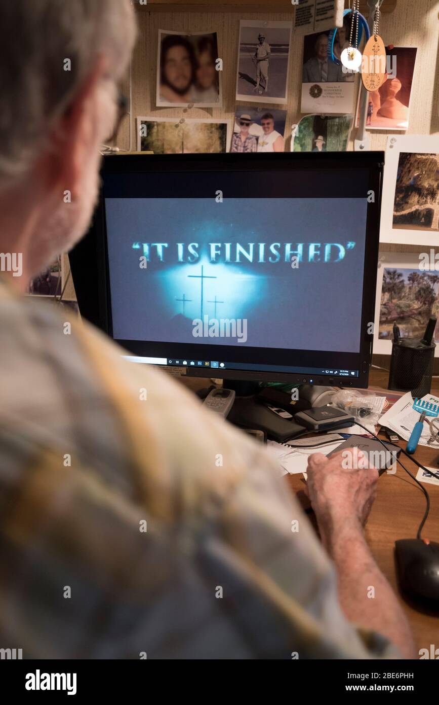 Homme regardant des services d'église virtuelle le dimanche de Pâques sur un ordinateur à la maison pendant Coronavirus, Covid-19 pandémie. Banque D'Images