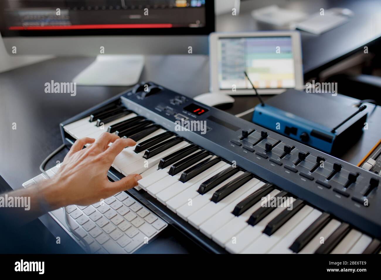 compositeur se charge des touches de piano dans le studio d'enregistrement. technologie de production musicale, l'homme travaille sur pianino et clavier d'ordinateur sur le bureau. gros plan Banque D'Images