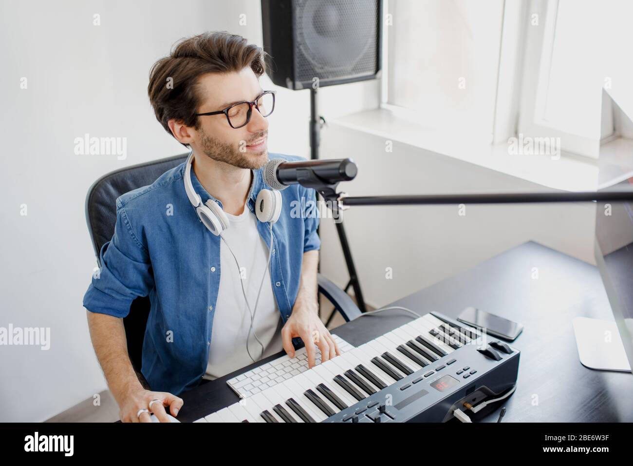 L'homme joue de la guitare et chante et produit une bande-son ou une piste  électronique dans le projet à la maison. Arrangeur de musique masculine  composant la chanson sur midi piano et