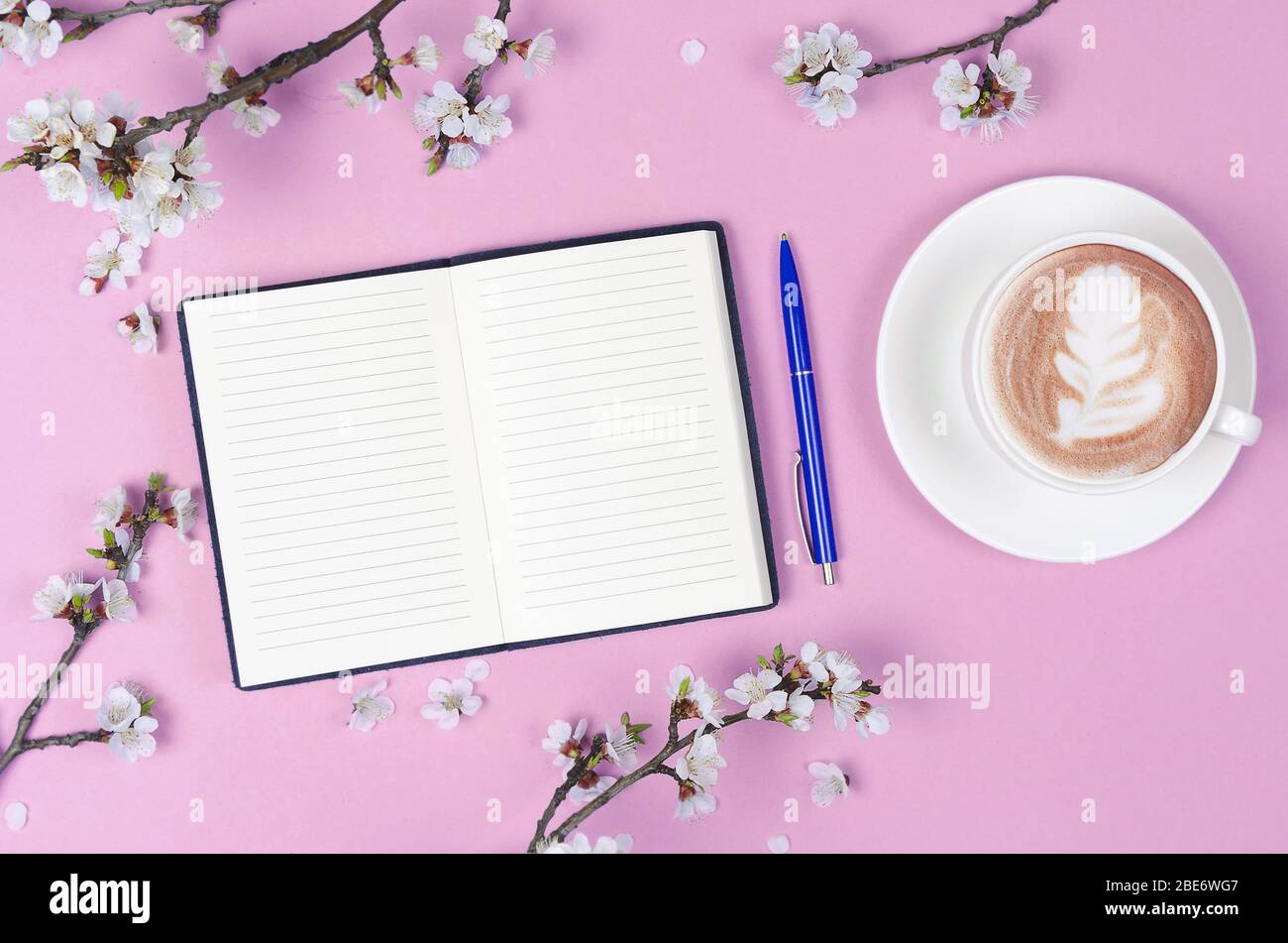 Liste de souhaits pour les plans futurs. composition de plat avec fleurs et bloc-notes et café avec art du café Banque D'Images