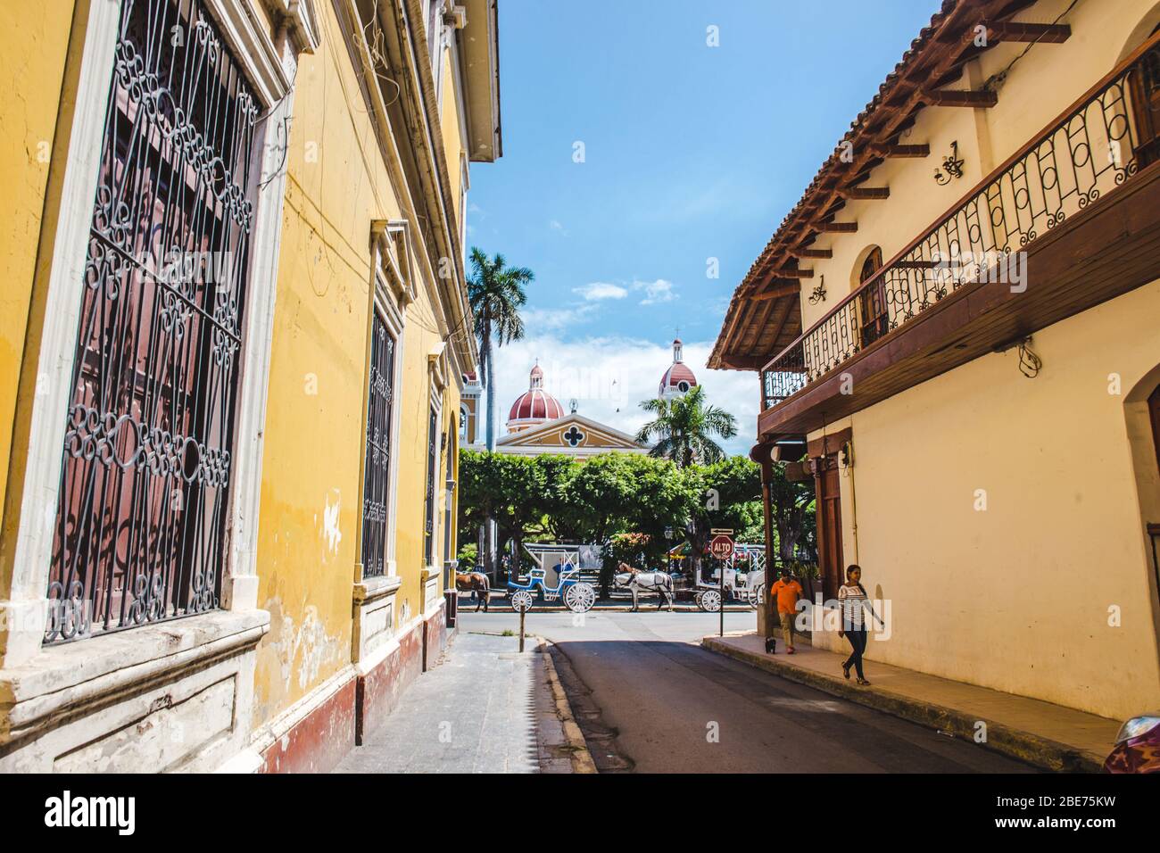 Rue latérale menant à l'architecture coloniale jaune de la place principale, Parque Central de Grenade, Nicaragua Banque D'Images