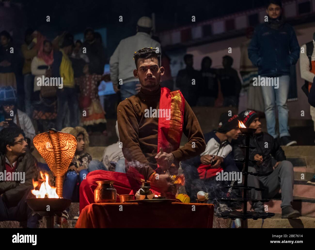 Jeune homme dévot à Varanasi, Inde, exécutant Aarti avec des pétales sur ses cheveux Banque D'Images