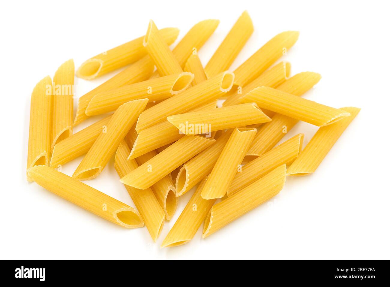 Tas de pâtes maison de penne sur fond blanc isolé dans la vue de dessus macro. Penne ressemble à un tube et ont une couleur jaune. Les pâtes sont de délicieux tradi italien Banque D'Images