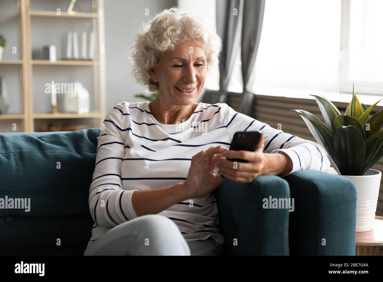 Heureuse femme souriante au téléphone, regardant l'écran Banque D'Images
