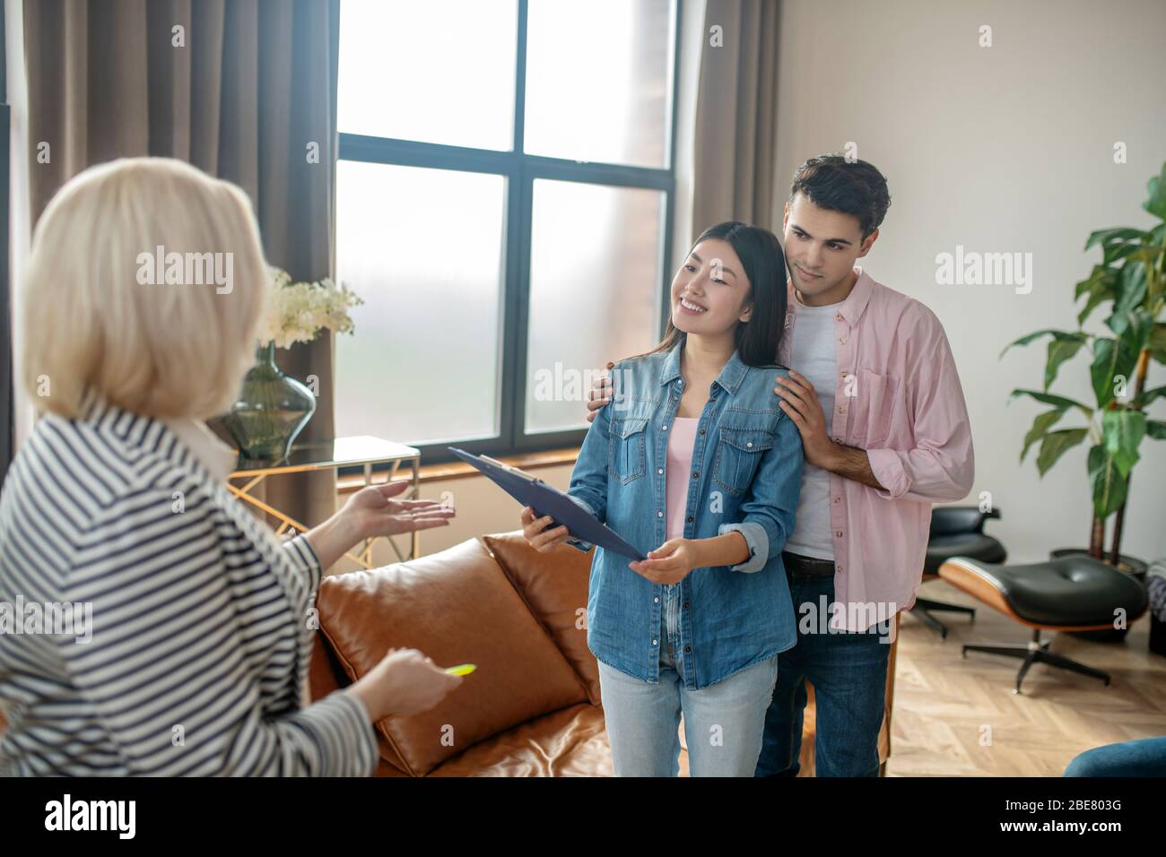 Couple jeune. Homme grand à poil foncé et sa petite amie parlent au psychologue dans son cabinet Banque D'Images