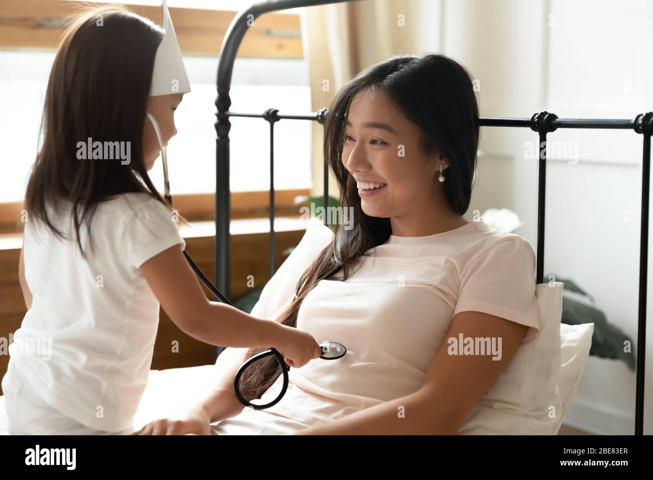 La petite fille asiatique tient le phonendoscope écoute les battements de cœur à la mère Banque D'Images