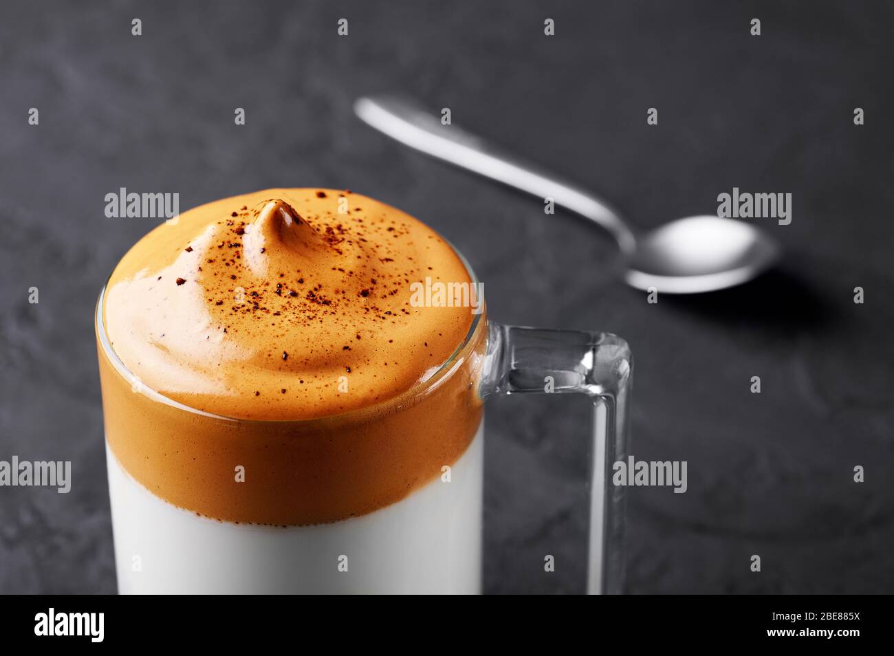 Le café Dalgona dans une tasse transparente sur le plateau noir en ardoise. Le café de Dalgona est une boisson sud-coréenne avec du café instantané fouetté, du sucre et du mil Banque D'Images