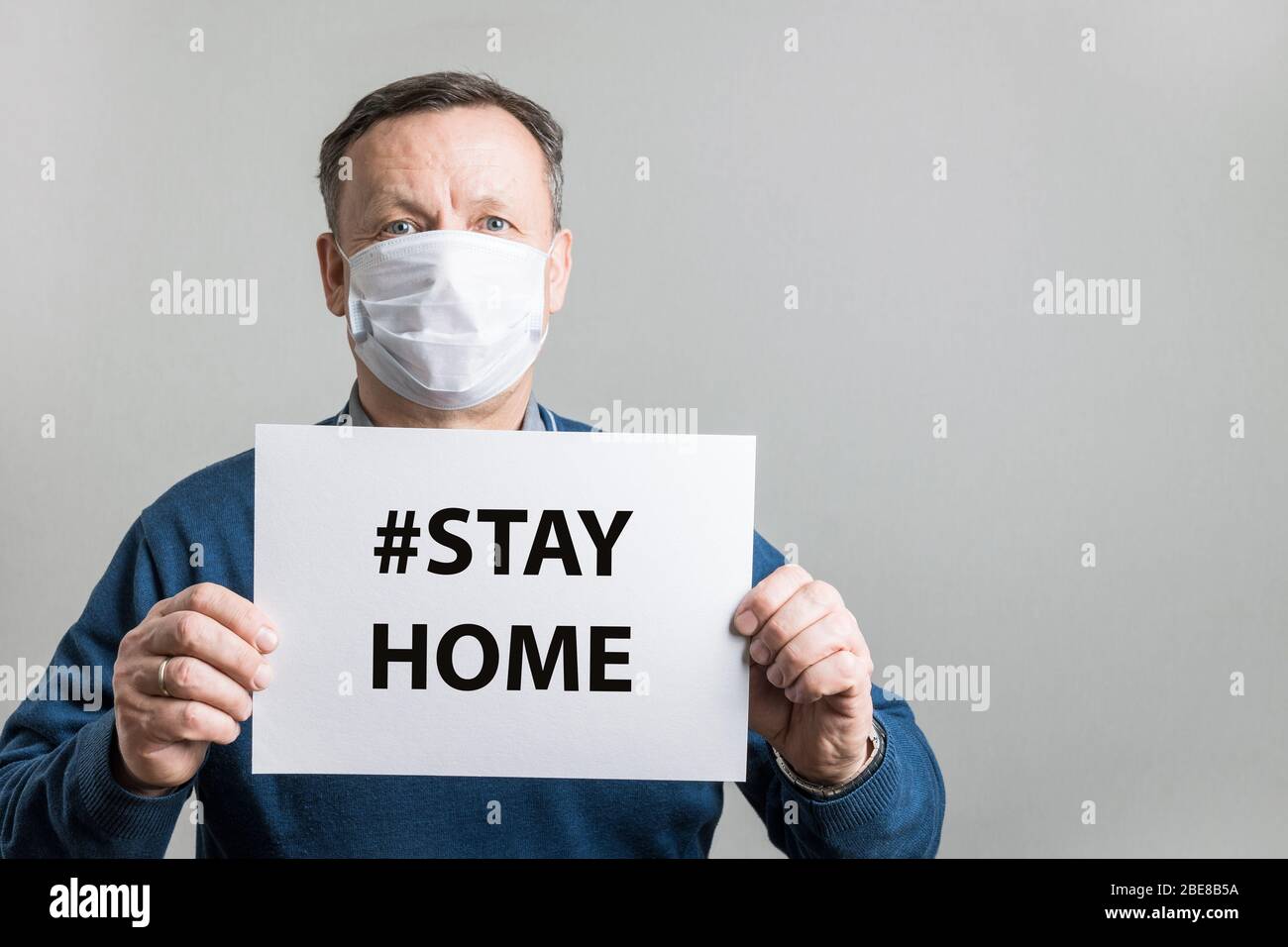 Homme adulte dans un masque médical de protection, blanc pour le texte - RESTER À LA MAISON. Covid-19. Concept de quarantaine. Prévention du coronavirus. Banque D'Images