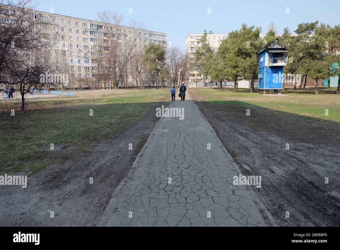 Une route sèche et sèche avec femme et petit garçon, debout sur la fin de l'ombre, créée par le soleil. Bâtiments ukrainiens typiques autour dans la capitale de Banque D'Images