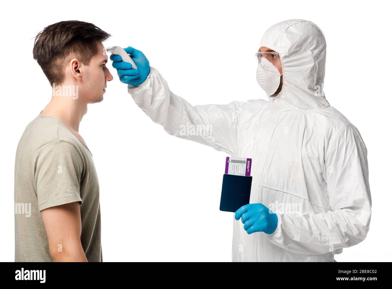 médecin dans un équipement de protection individuelle tenant pyromètre et passeport avec carte d'embarquement près de l'homme isolé sur blanc Banque D'Images