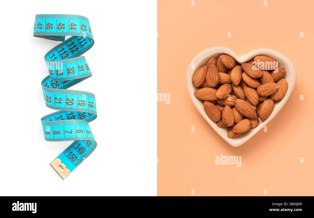 Disposition créative de ruban bleu centimètre sur un fond blanc et d'amande dans un bol en coeur sur un fond rose pastel. Le concept de régime et de weig Banque D'Images