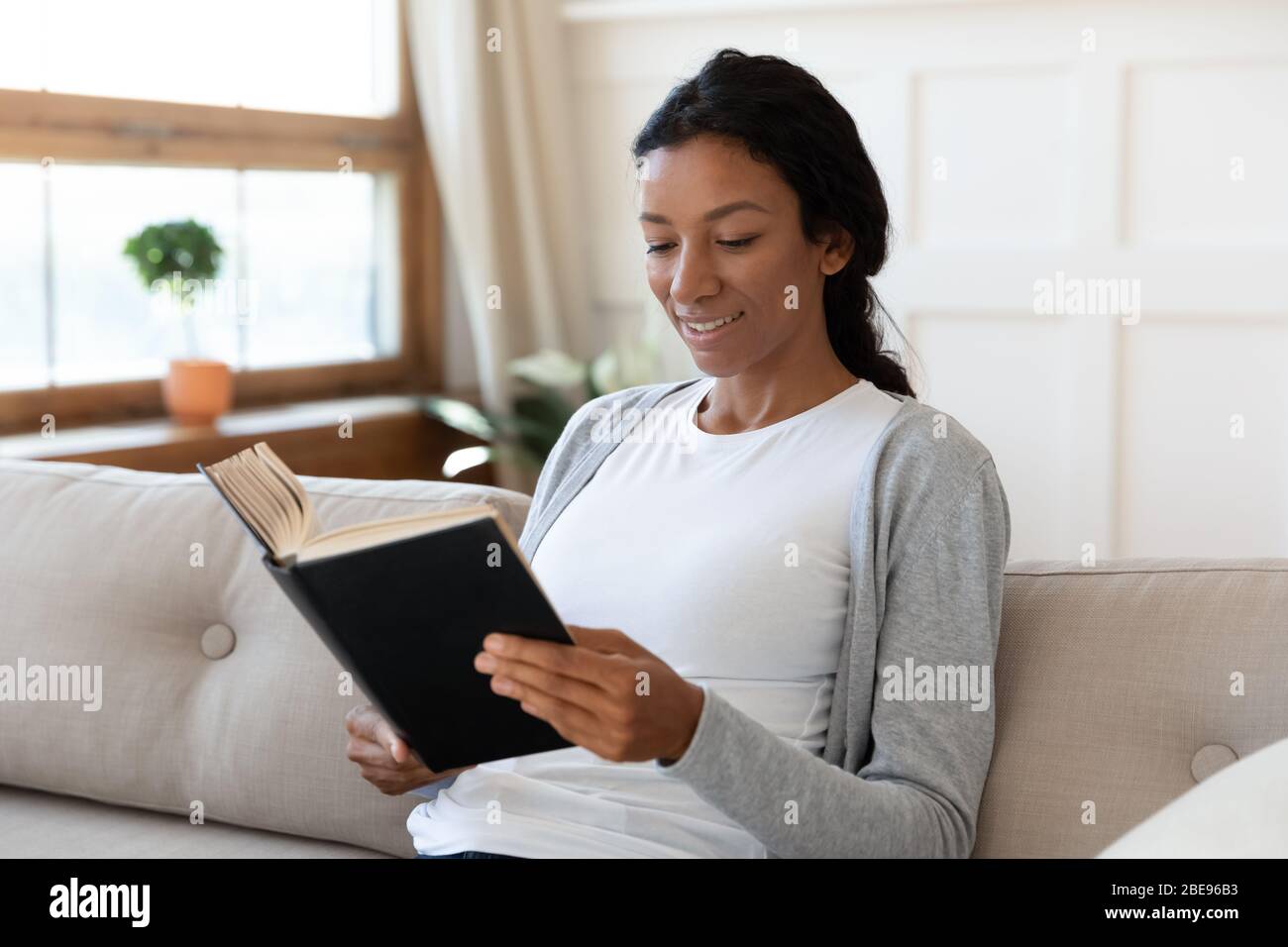 Calme fille africaine américaine souriant et lire un livre Banque D'Images
