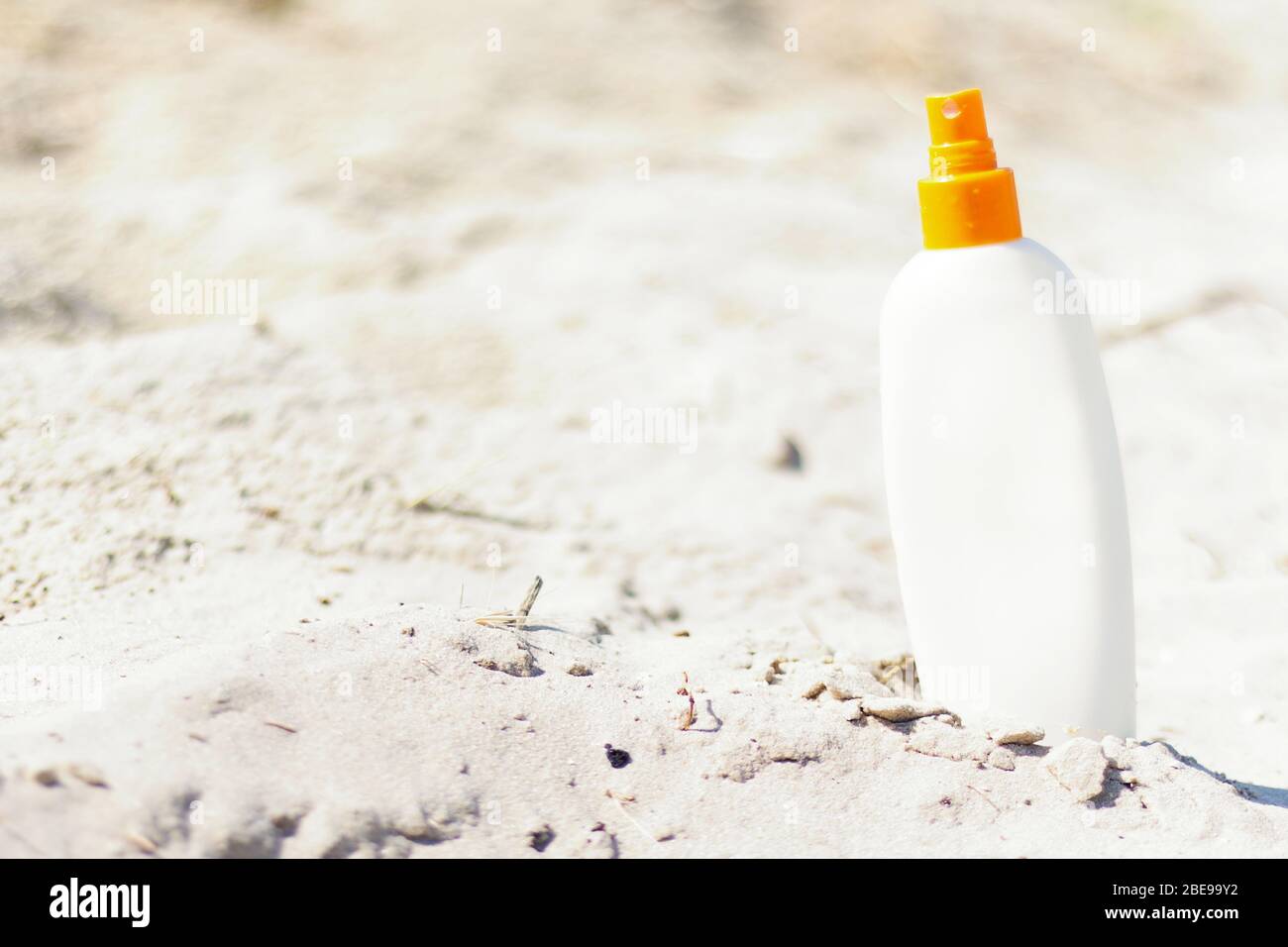 Maquette pour crème solaire sur la plage tropicale sauvage avec sable naturel. Bouteille de crème solaire blanche. Été, vacances, concept de voyage. Espace de copie. Banque D'Images