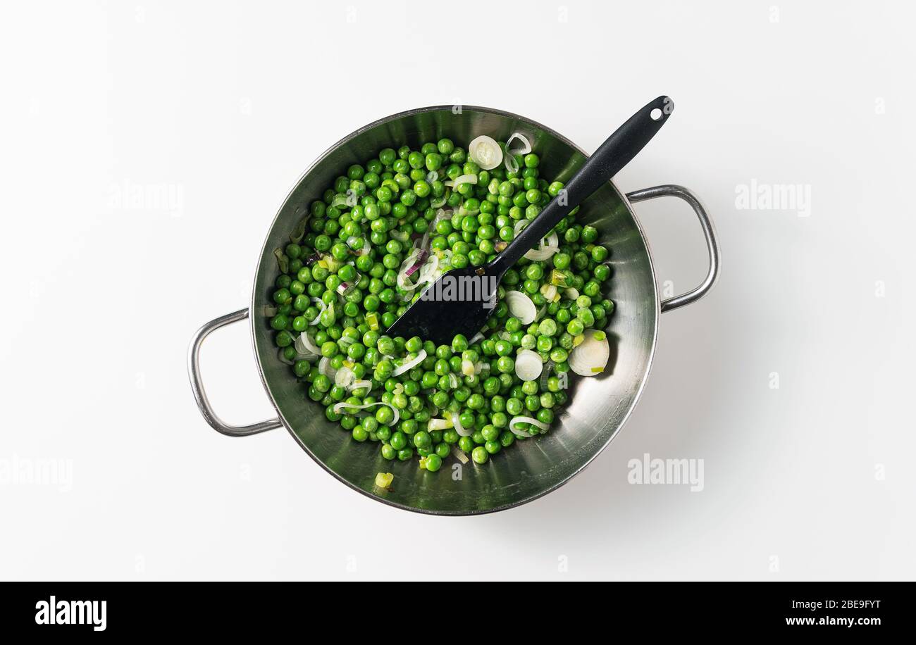 cuisson des petits pois avec des oignons verts dans une poêle. recette de printemps Banque D'Images