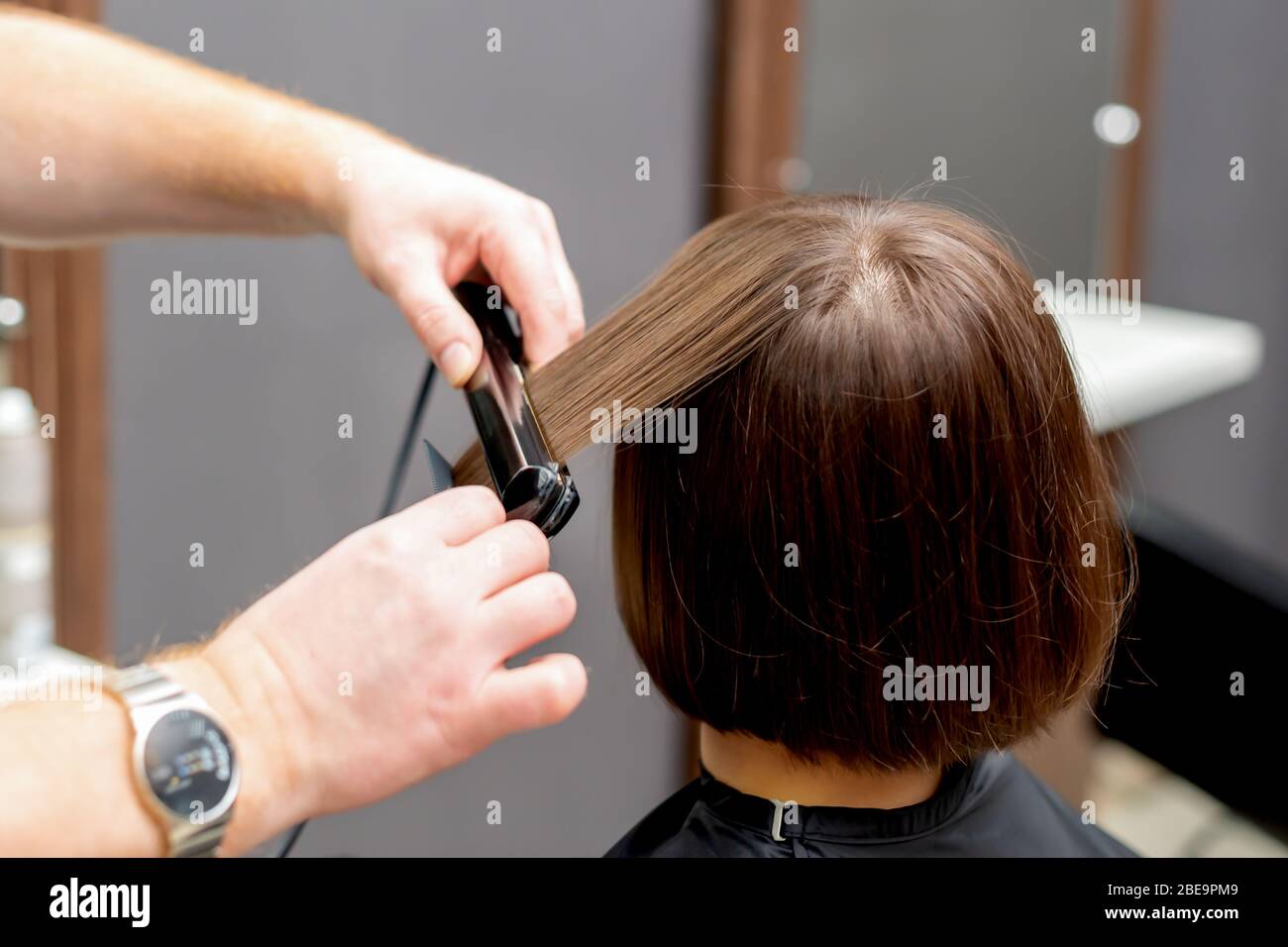 Coiffeur redresse les cheveux de la femme avec un lisseur de cheveux dans  le salon de coiffure Photo Stock - Alamy