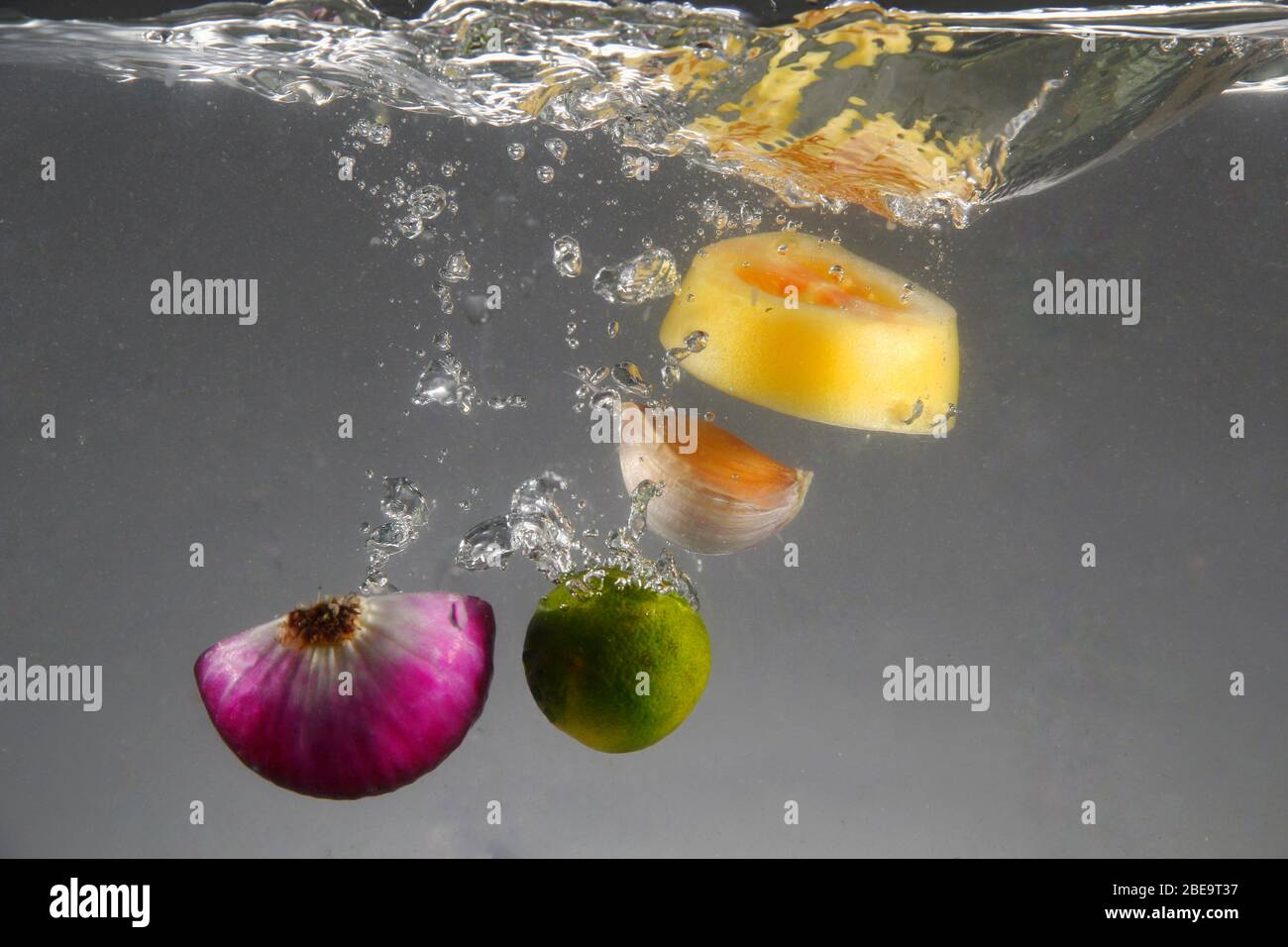 Photo de l'oignon rouge, de l'ail, de la tomate et du calamansi lâché dans l'eau Banque D'Images