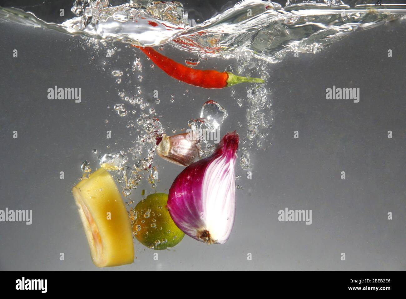 Photo de l'oignon rouge, du piment rouge, de l'ail, de la tomate et du calamansi dans l'eau Banque D'Images