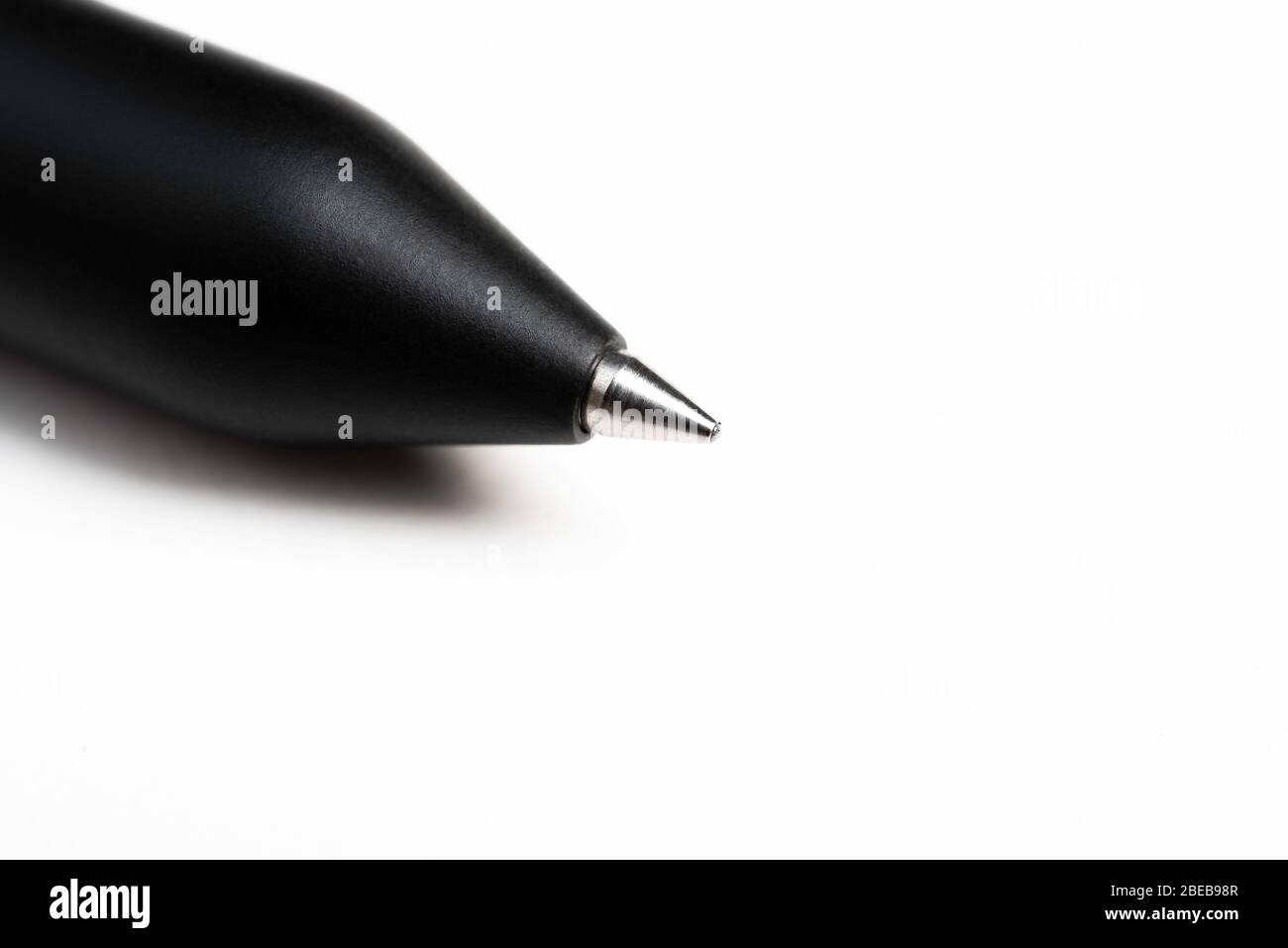 Macro-shot de la pointe d'écriture avec une partie du corps d'un stylo bille noir moderne et profilé sur fond blanc. Banque D'Images