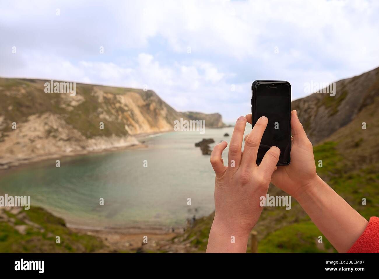 Les femmes prennent une photo sur un smartphone de Man O'War Beach à côté de Durdle Door sur la côte jurassique, en Angleterre du Sud. Banque D'Images