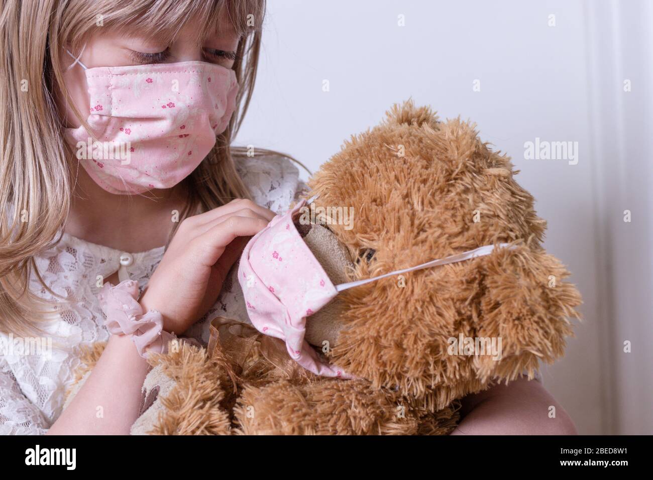 petite fille avec covid 19 maison de protection jouant avec son ours en peluche Banque D'Images