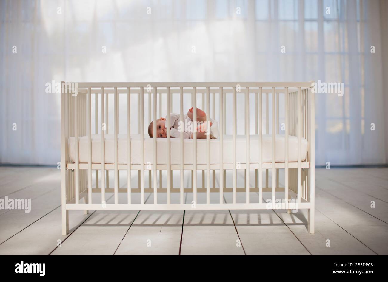 Un petit garçon mignon allongé sur son côté dans un lit de bébé Banque D'Images