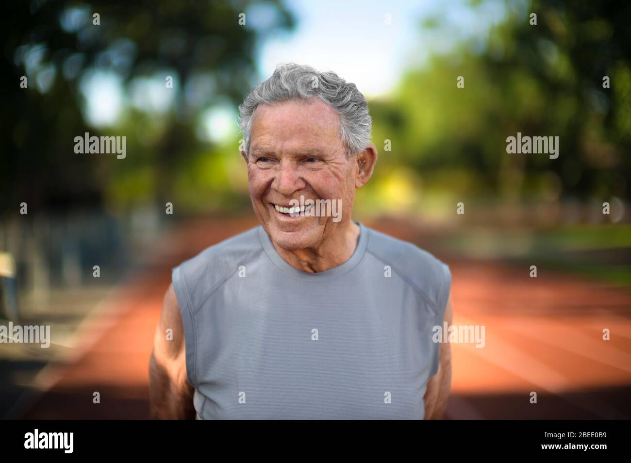 Portrait d'un homme souriant et mûr debout sur une piste d'athlétisme. Banque D'Images