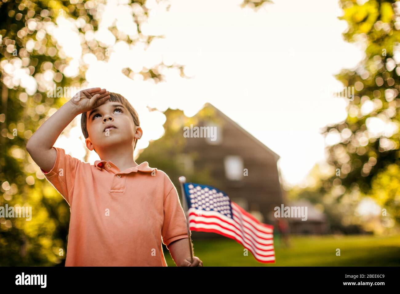 Jeune garçon salue tout en tenant un drapeau américain Banque D'Images