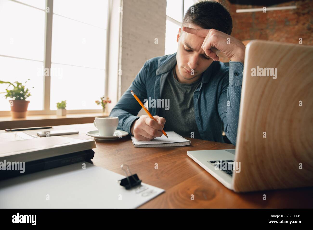 Espace de travail créatif - espace de travail organisé comme vous le souhaitez pour vous inspirer. Homme travaillant au bureau dans une tenue confortable, une position détendue et une table désordonnée. Choisissez l'atmosphère que vous voulez - idéal clair ou chaos. Banque D'Images