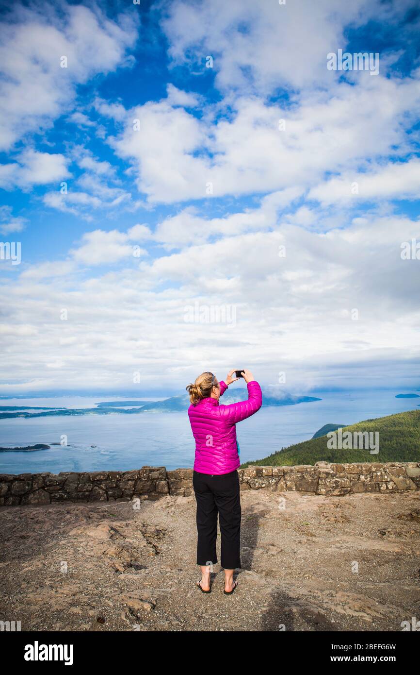 Une femme prenant des photos au sommet du Mont Constitution sur Orcas Island, Washington, États-Unis. Banque D'Images