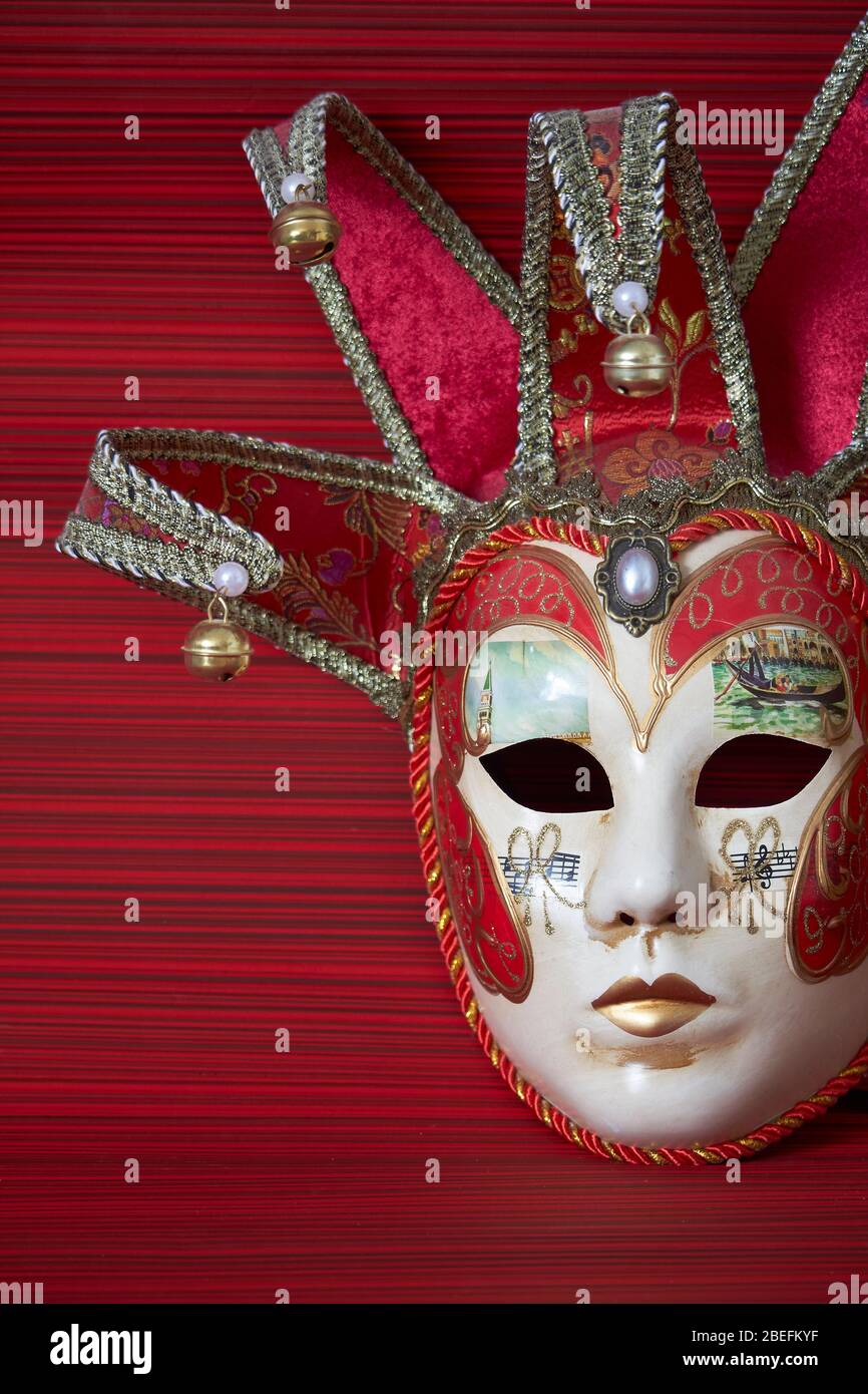Masque traditionnel vénitien carnaval, décor riche sur fond rouge, foyer sélectif Banque D'Images