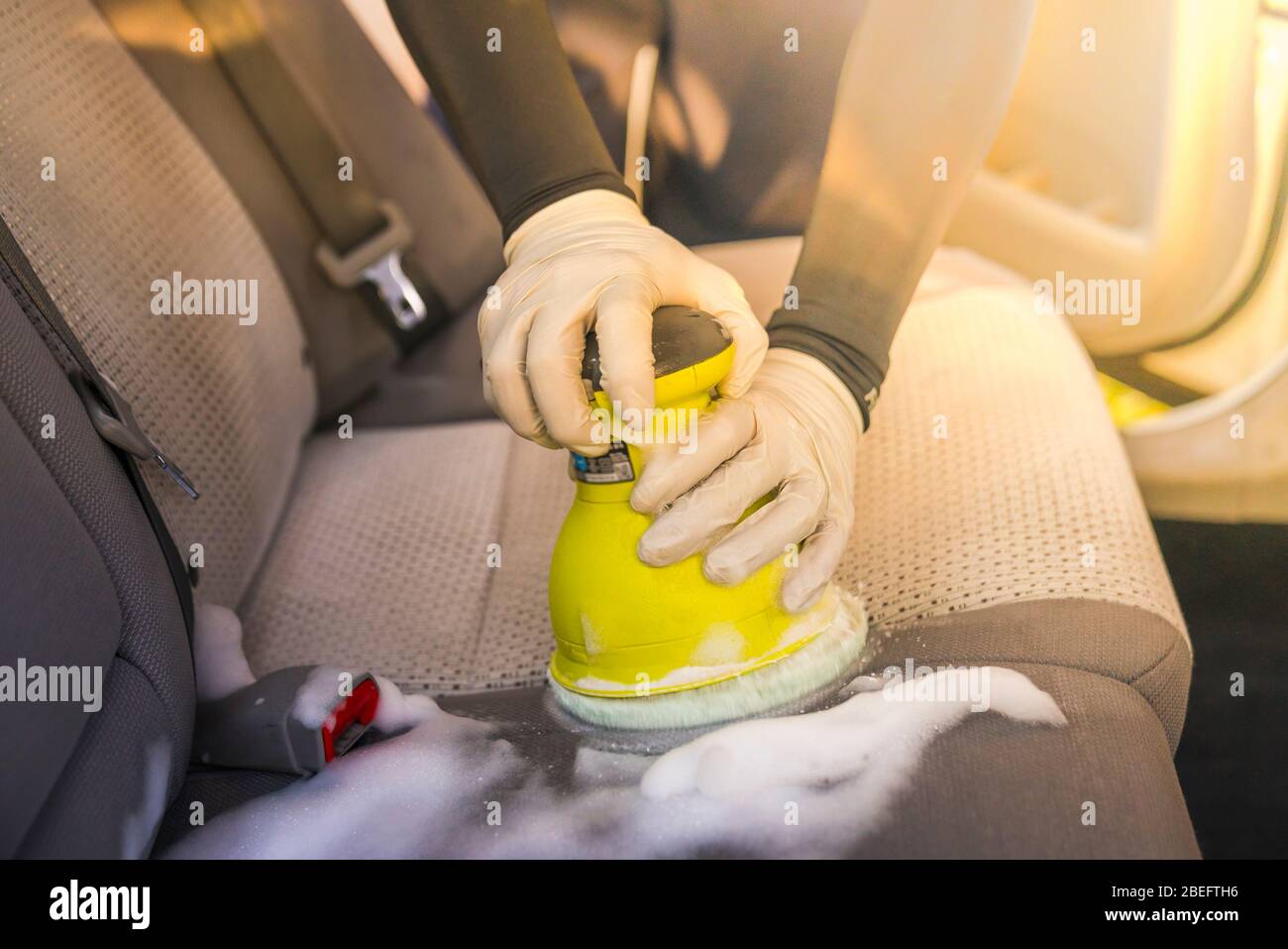Un homme d'intérieur de voiture de nettoyage par l'utilisation de produits chimiques de lavage et de mousse machine. Banque D'Images