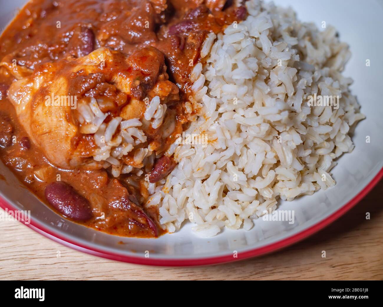Faites le plein d'eau et de vue rapprochée sur la mole de poulet de style sud-américain sucré et épicé et dînez de riz complet marron sain dans un bol de service rouge Banque D'Images