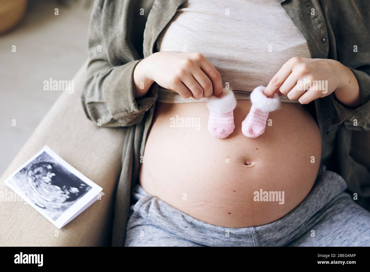 Gros Plan Sur Une Femme Enceinte Non Reconnaissable Avec De Jolies Chaussettes Pour Venir Bebe Sur Son Ventre Image D Echographie Fœtale Sur Le Coude Du Canape Photo Stock Alamy