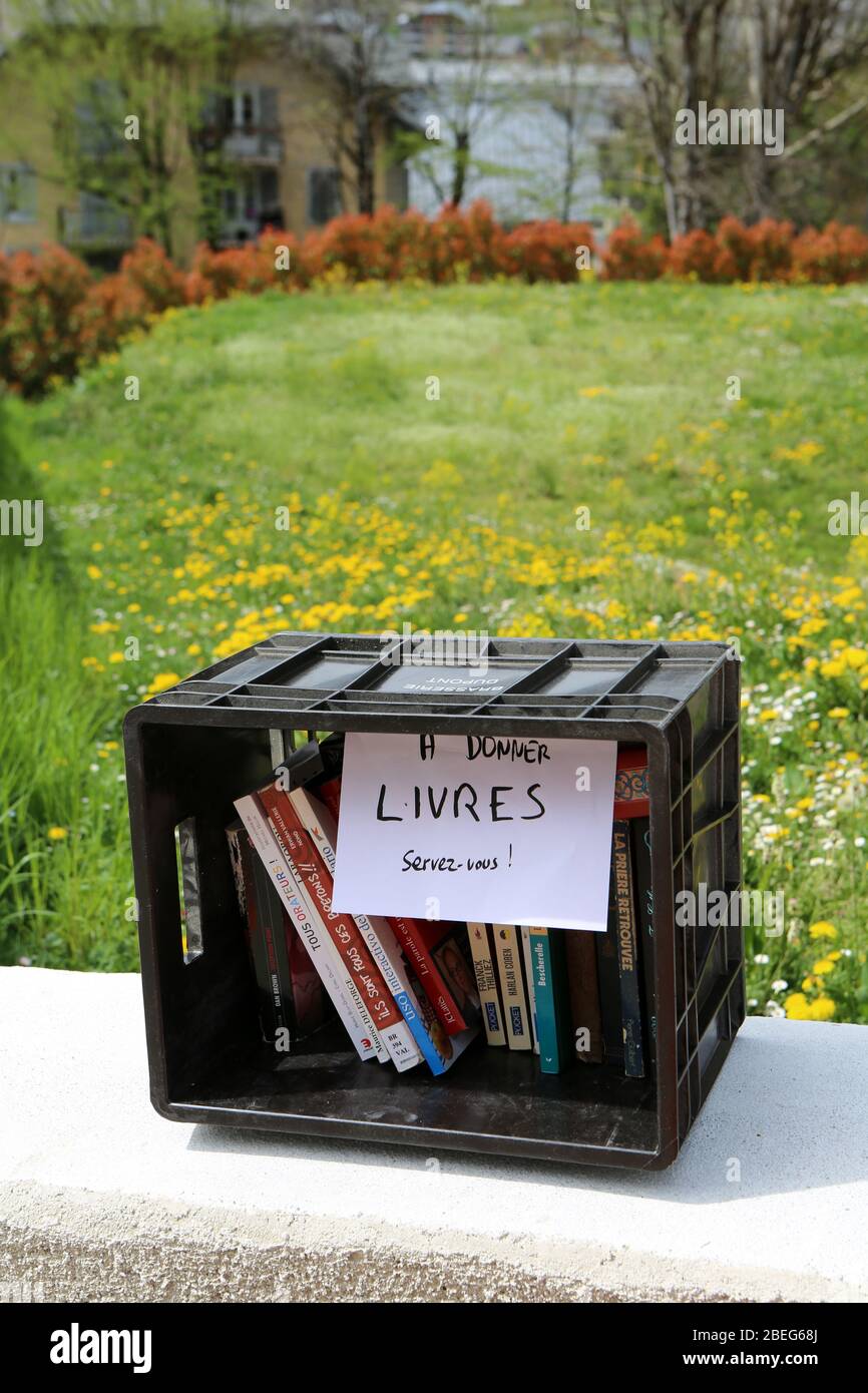 Caisse en plastique noire sur un muret comprant des livres à donner. Saint-Gervais-les-bains. Haute-Savoie. France. Banque D'Images