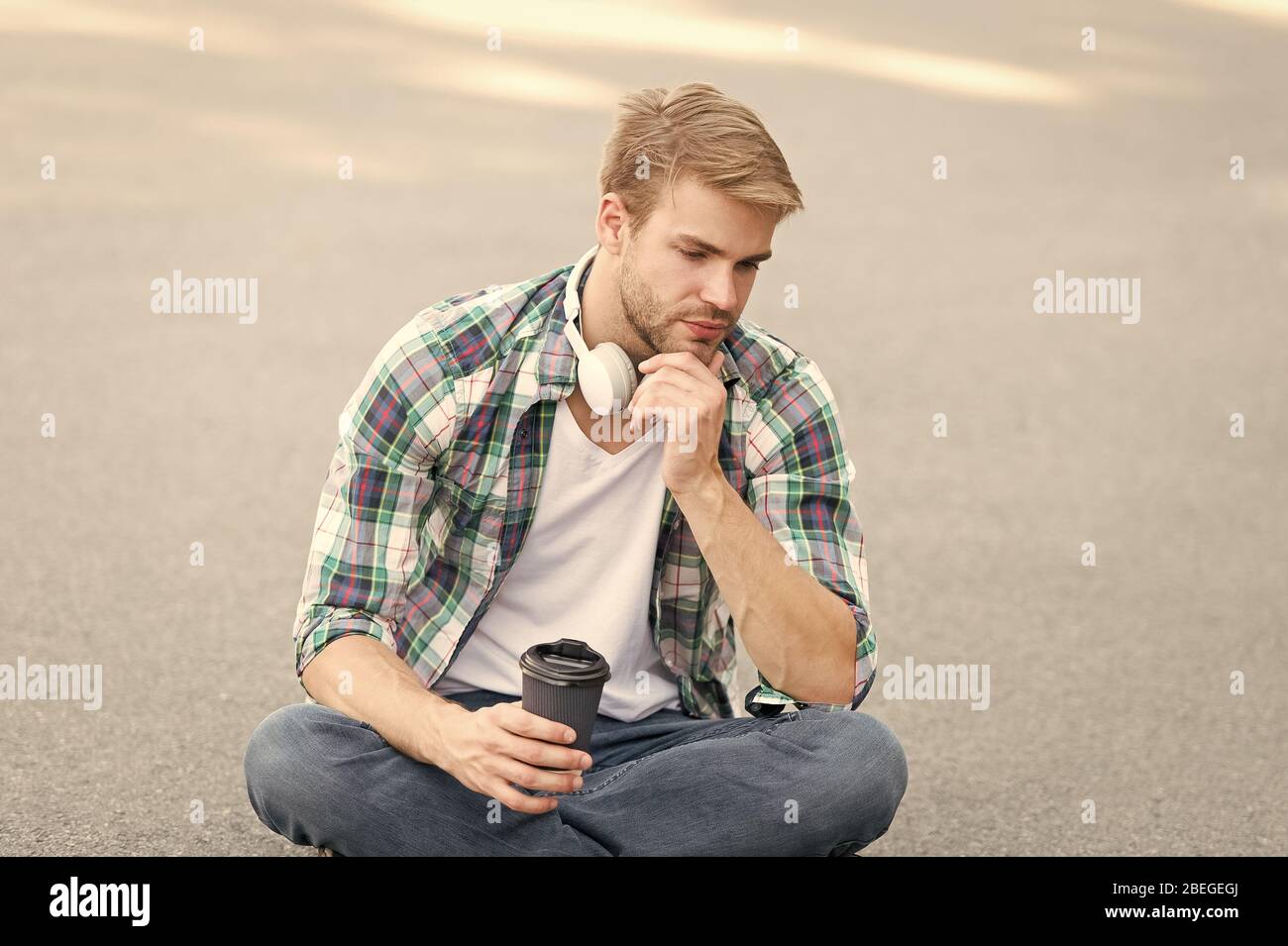 Plus de café. café d'aller. guy boire un café en plein air. L'homme s'asseoir sur le sol. fatigué en étudiant casque. l'éducation en ligne. écouter la musique. ebook concept. homme Chemise à carreaux. élève se détendre et se ressourcer. Banque D'Images