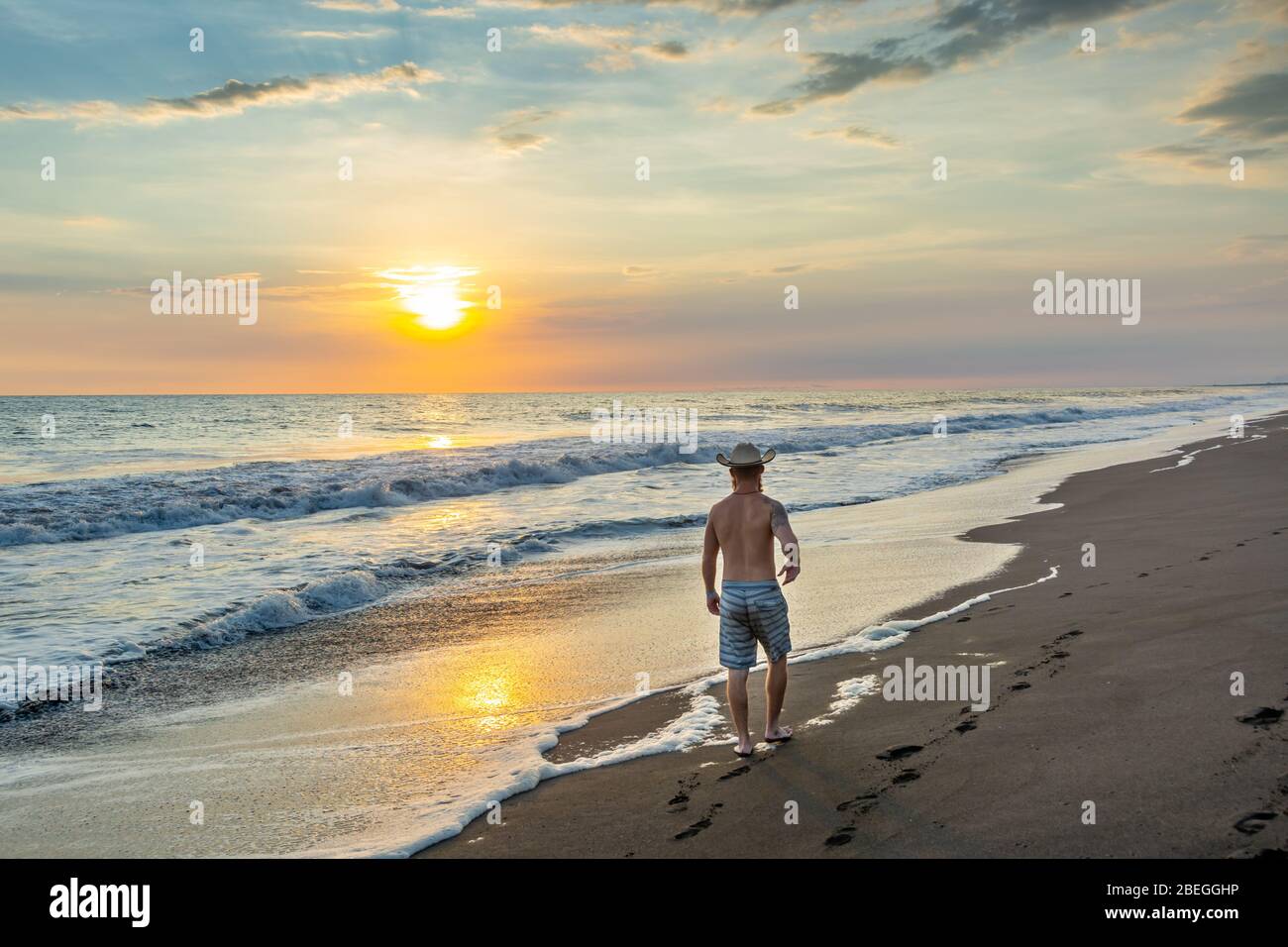 Long homme marchant au coucher du soleil sur la plage de Monterrico, Guatemala Banque D'Images