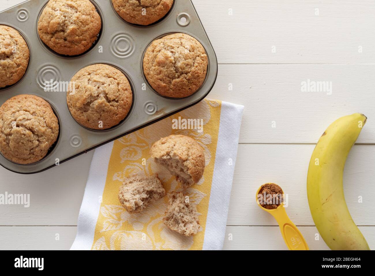 Muffins aux noix de banane, banane, cannelle et serviette de cuisine sur fond de bois blanc avec espace de copie Banque D'Images