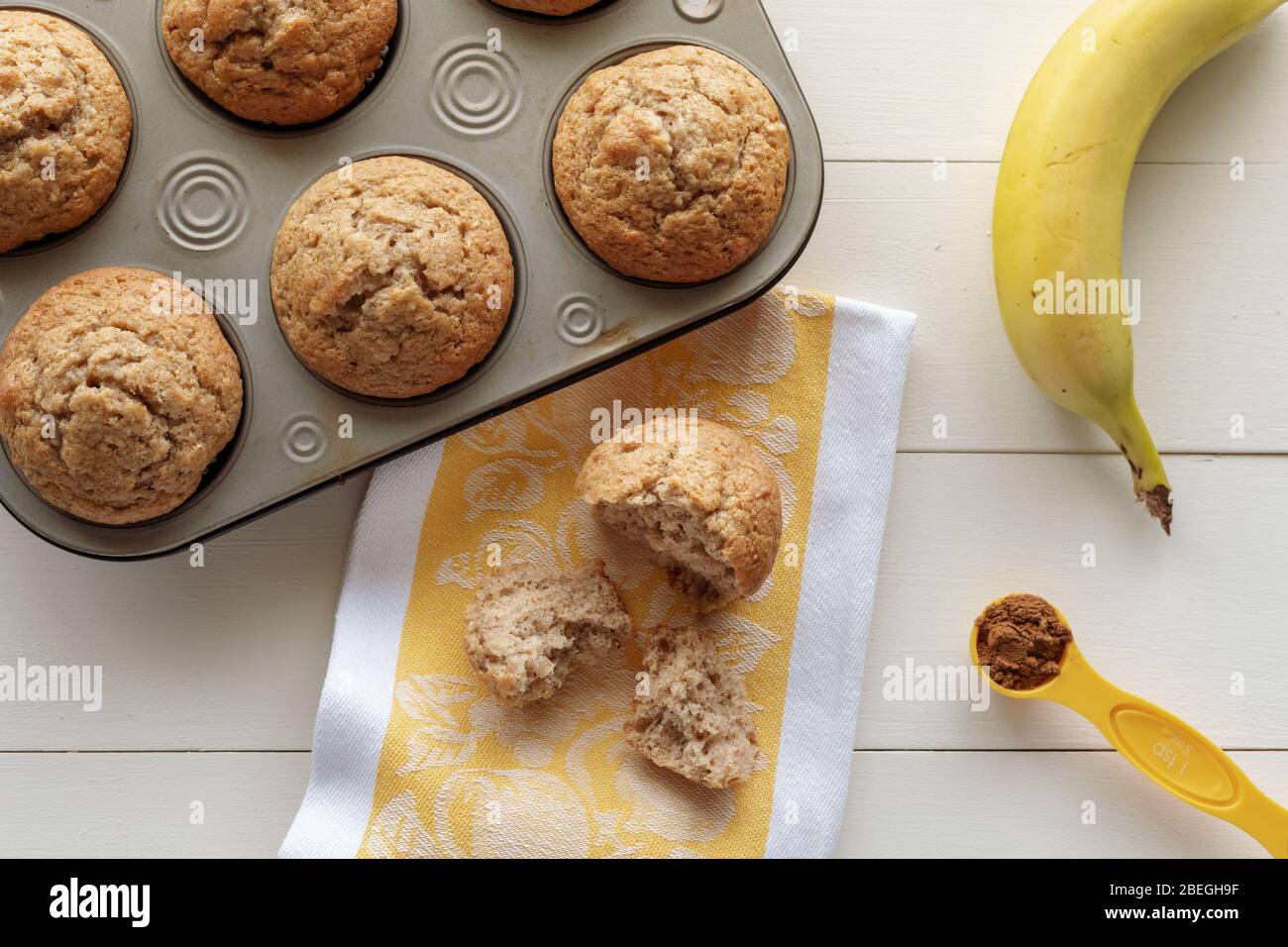 Muffins aux noix de banane avec une déchirée Apart et Banana, cannelle et serviette de cuisine sur fond de bois blanc Banque D'Images