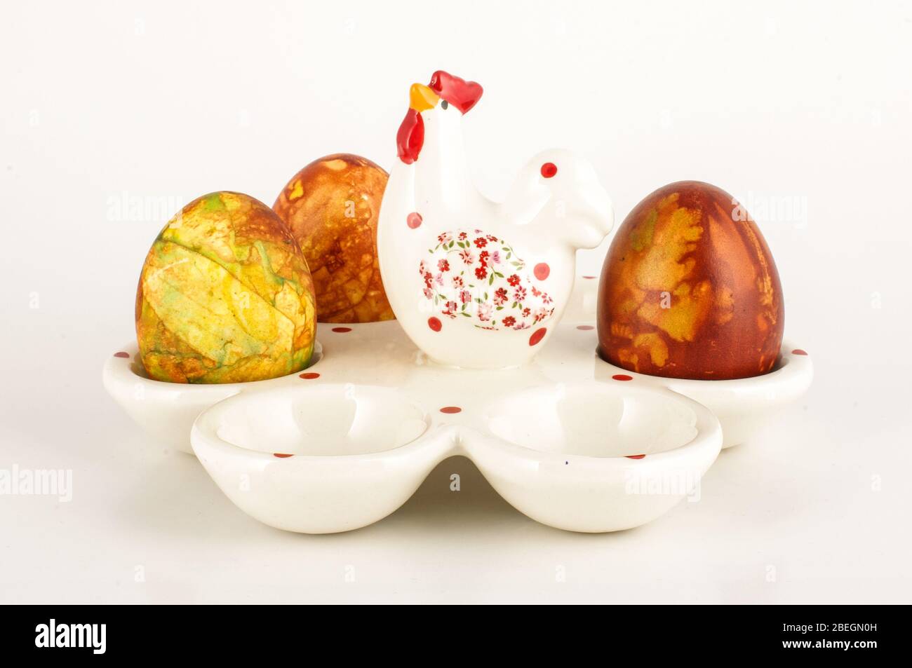 Support d'œufs en porcelaine blanche avec trois œufs de Pâques isolés sur fond noir Banque D'Images