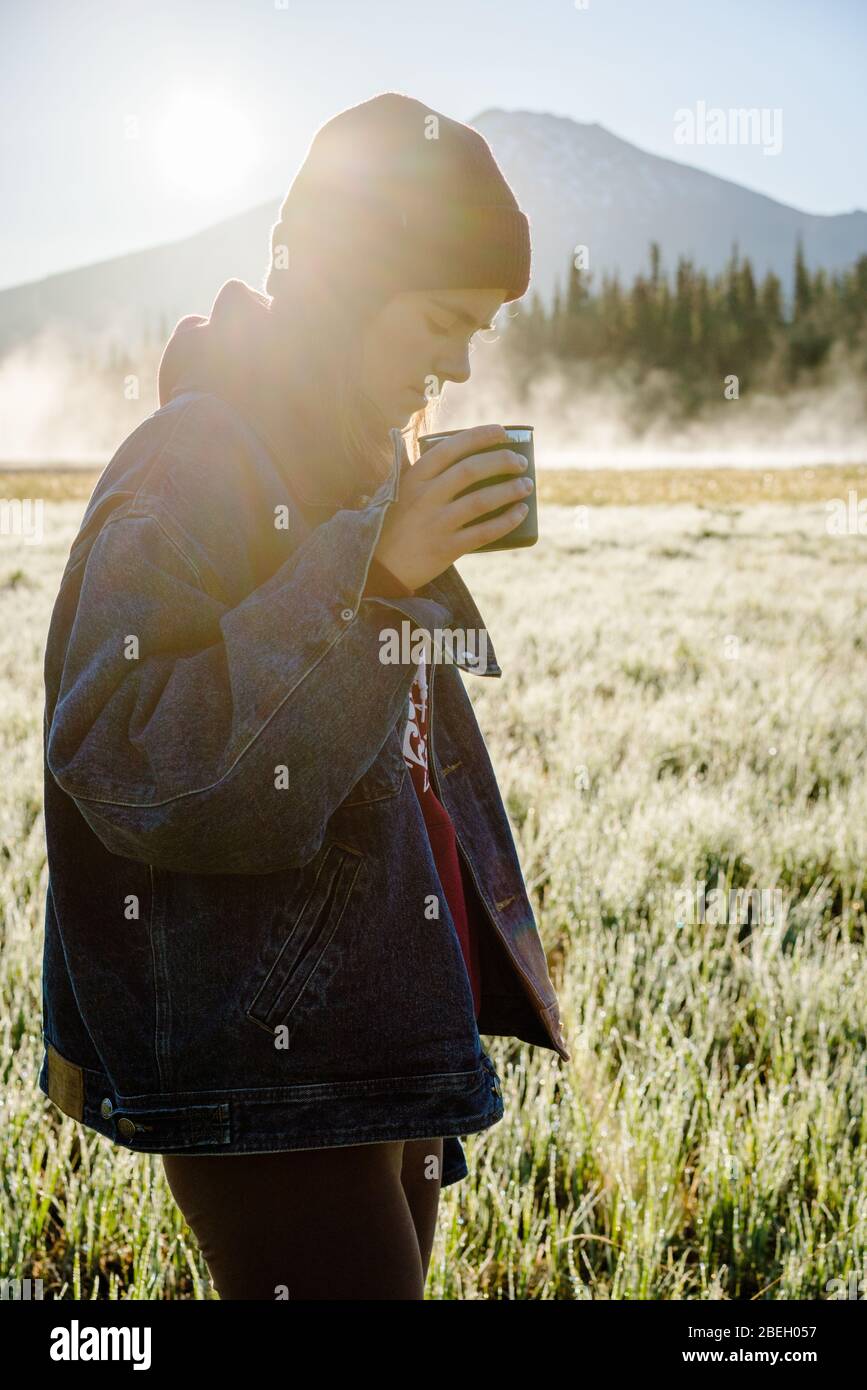 Image verticale de la jeune femme tenant une tasse réutilisable au lever du soleil Banque D'Images