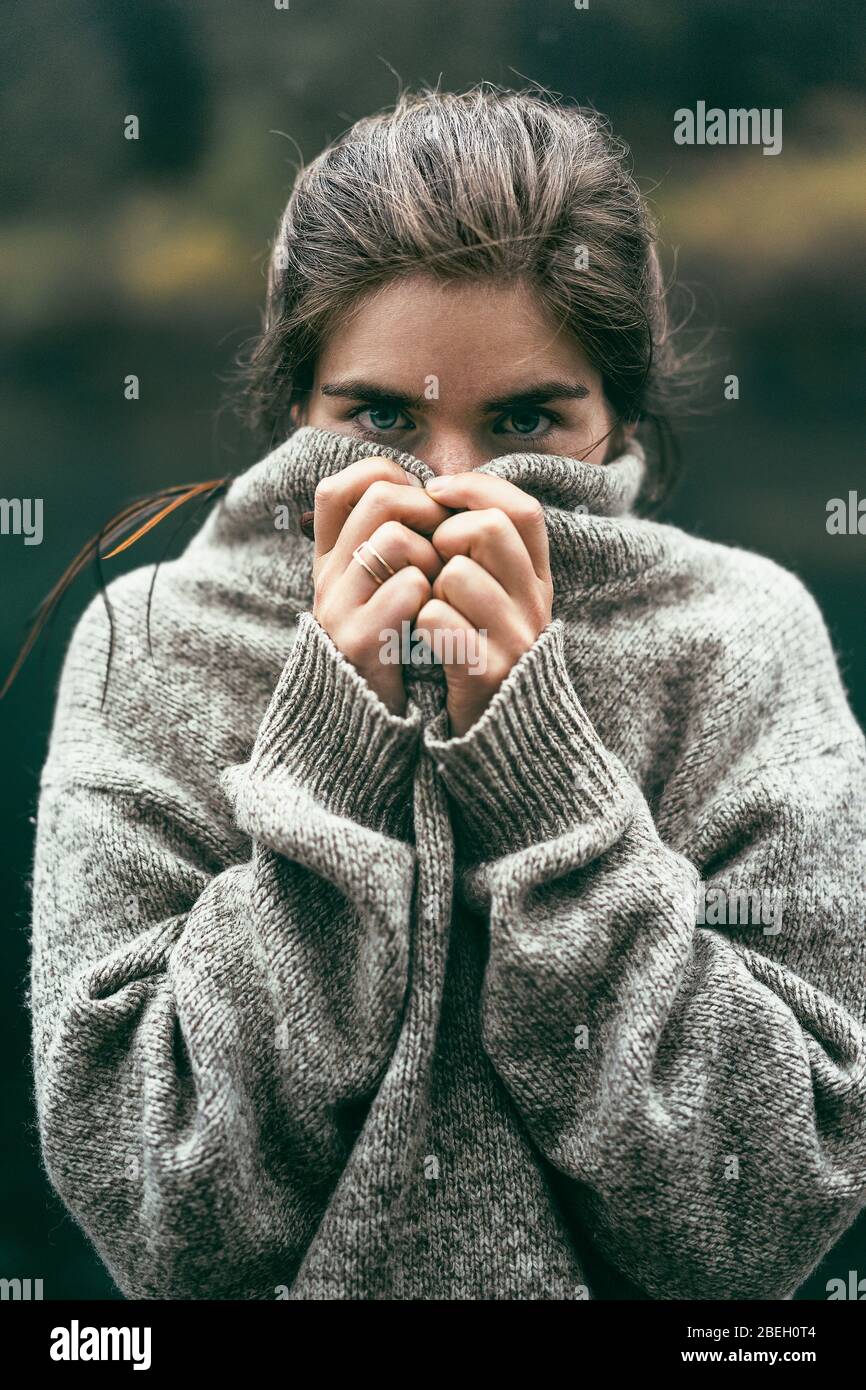 Portrait d'une jeune femme couvrant le visage avec un pull confortable Banque D'Images
