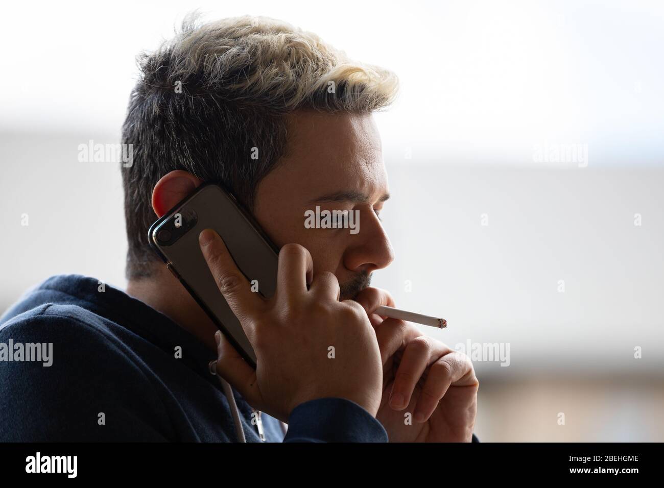 Portrait de l'homme fume la cigarette sur son téléphone. Banque D'Images