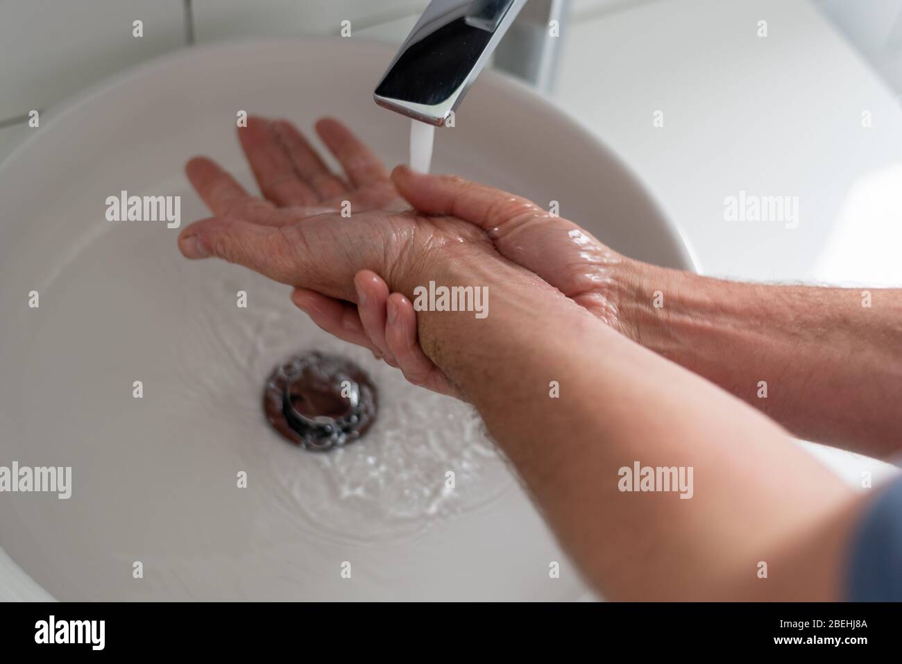 L'homme aux mains froissées se lave les mains pendant l'éclosion de Covid-19. Banque D'Images