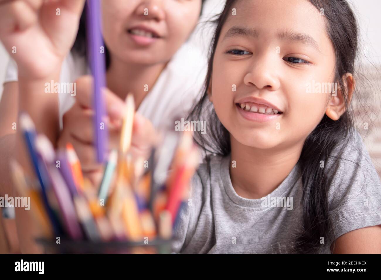 Petite fille asiatique picking un crayon de couleur avec maman. La mère et la fille partagent leurs vacances. Enfants apprentissage de la peinture avec parent. Banque D'Images