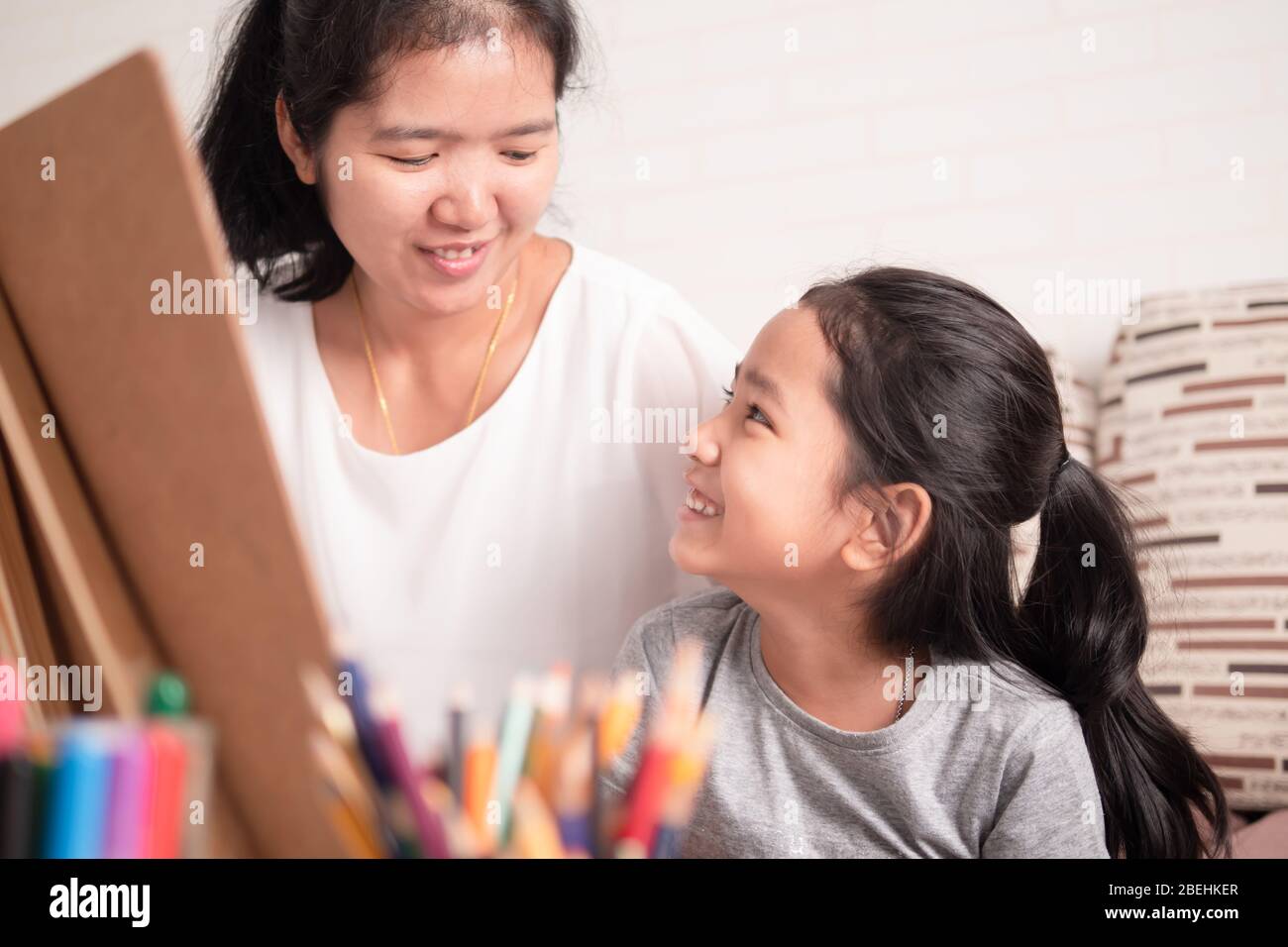 La mère et la fille partagent leurs vacances. Petite fille asiatique fraiseuse avec maman. Enfants apprentissage de la peinture avec parent. Banque D'Images