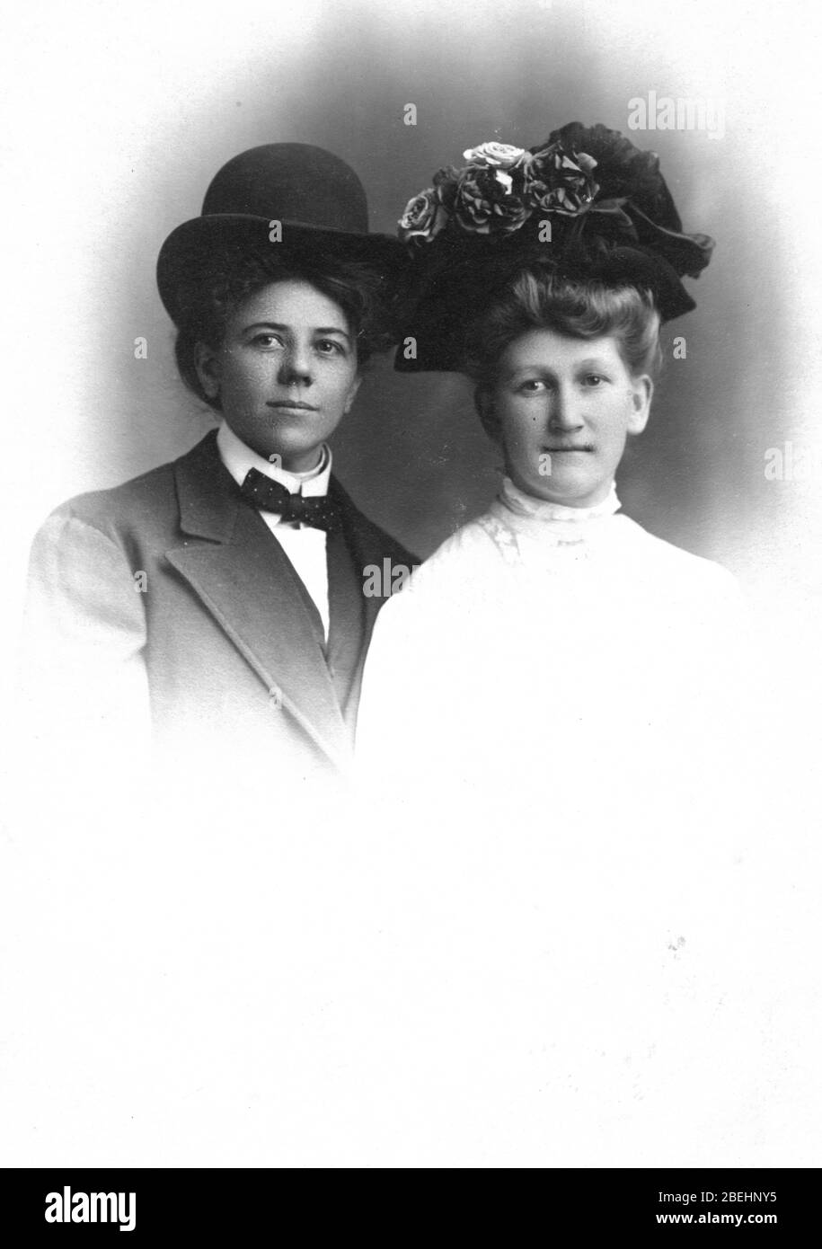 Deux femmes, toutes deux avec les coiffures pompadour, mais l'une est habillée comme un homme, c.c., Les deux sont finement habillés et regardent leurs pièces. Sont-ils un couple aimant, des sœurs? amis ? Gay ? Peut-être sont-ils habillés de costumes pour un jeu. Pour voir toutes mes images associées recherche: Prestor vintage gay Banque D'Images