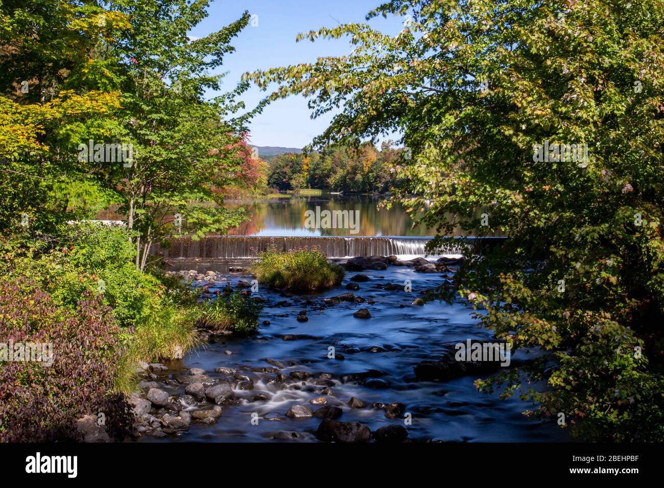 L'eau se rince sur un barrage en toile de fond de feuillage de début d'automne dans le Vermont, Banque D'Images
